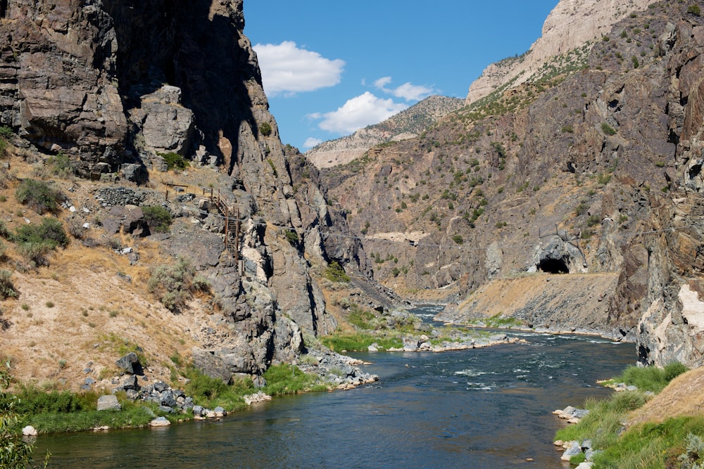 gray rocky mountain beside river under blue sky during daytime