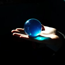 Close-up of hands gently holding a glowing, transparent sphere representing care and transparency.
