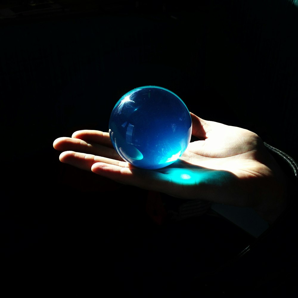 person holding blue ball with light