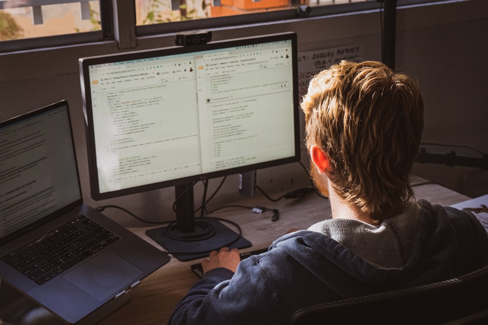 man in black jacket sitting in front of computer