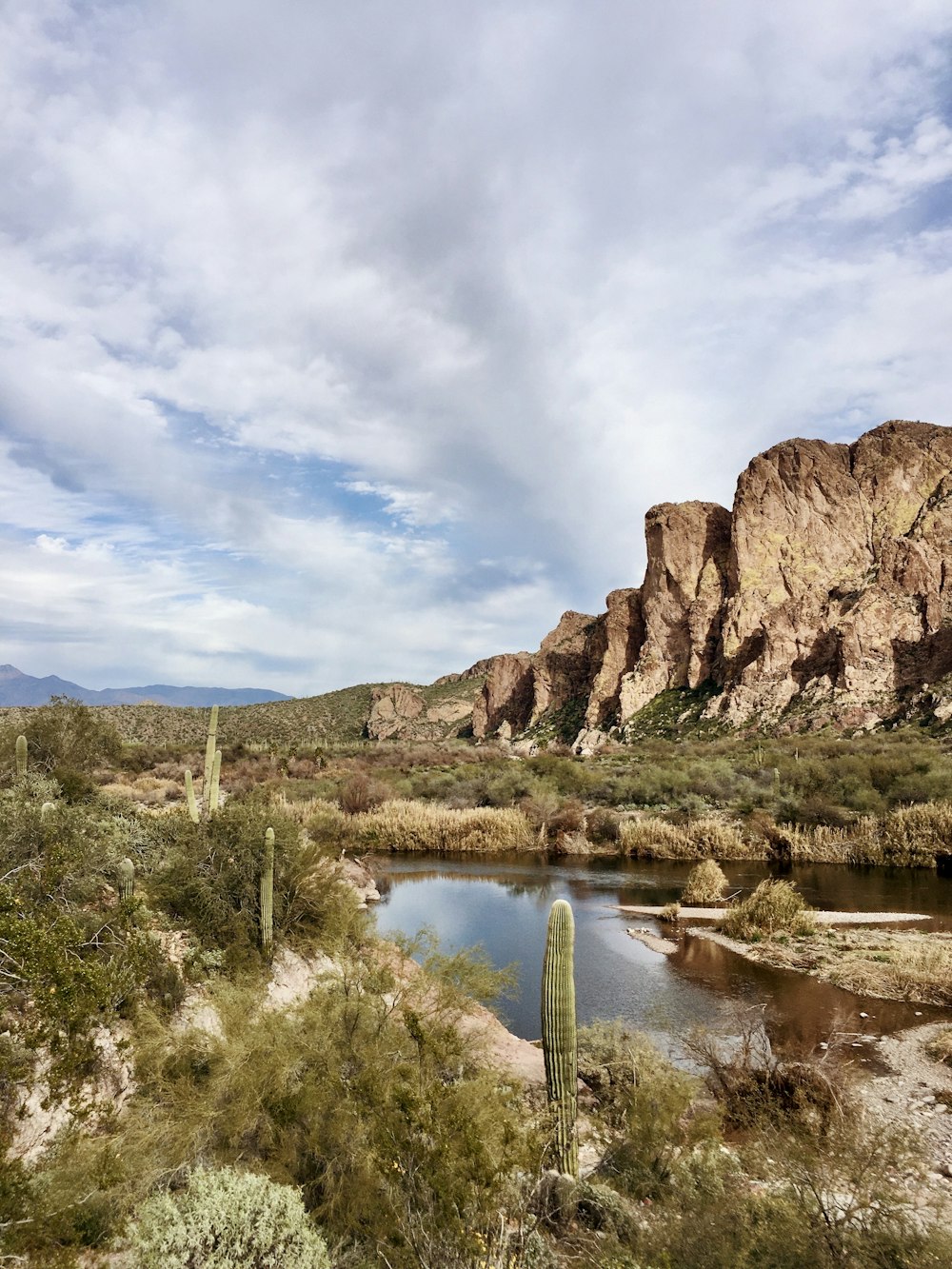 brown rocky mountain beside river under blue sky during daytime