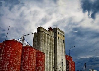 A modern grain storage facility with trucks loading soybeans under a bright sky.