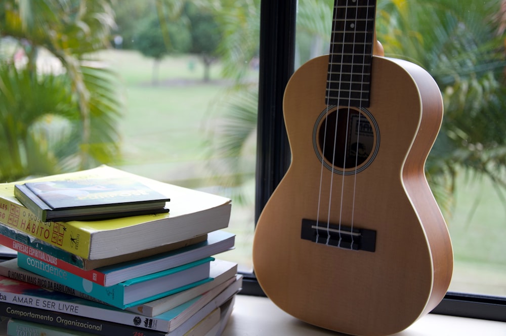 brown acoustic guitar on books