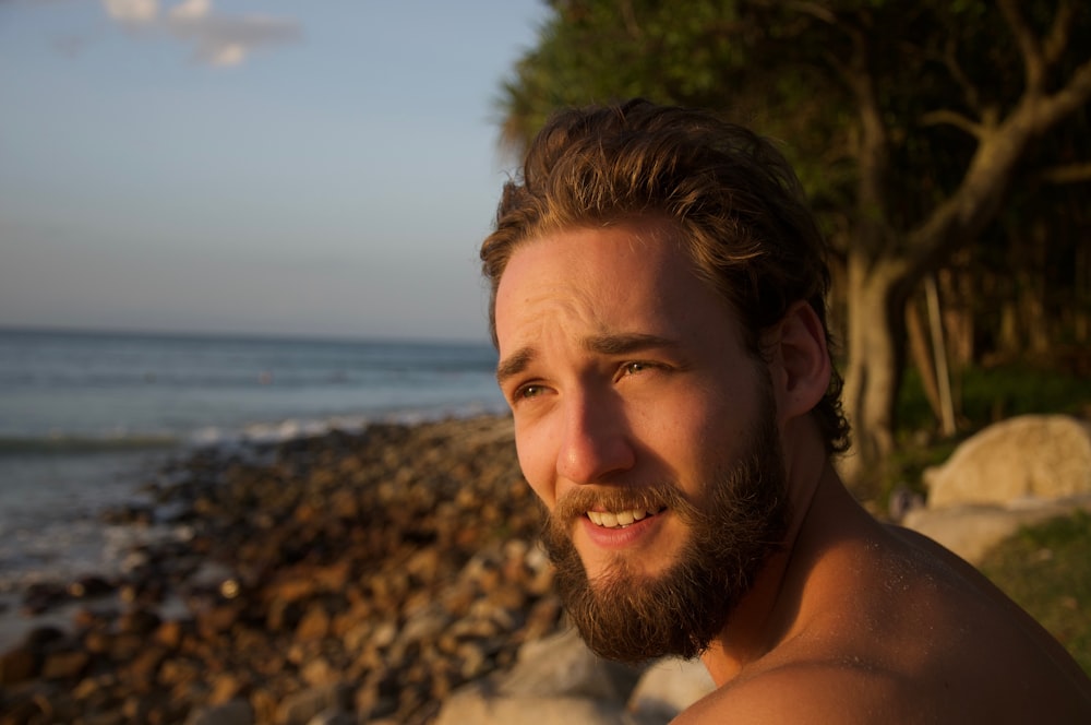 topless man standing on beach during daytime