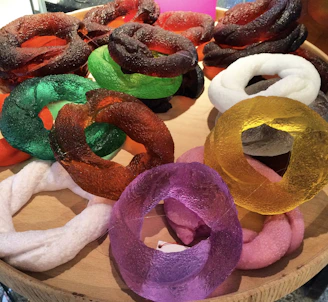 A collection of colorful artificial gemstone rings displayed on a wooden tray.