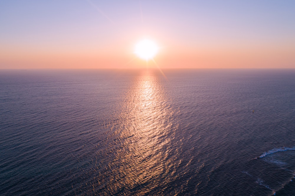a large body of water with a sun setting in the background