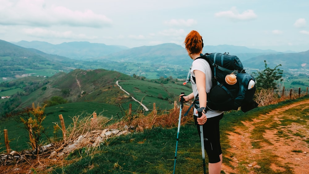 woman in black t-shirt and black backpack holding black and white stick standing on brown