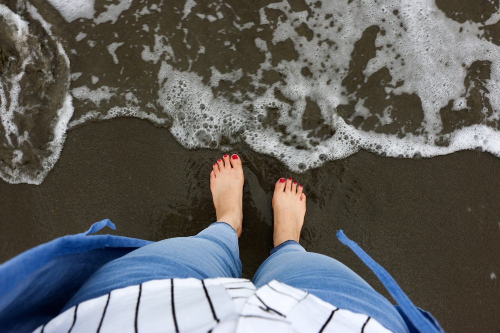 해변 해안에 서 있는 파란색과 흰색 바지를 입은 사람