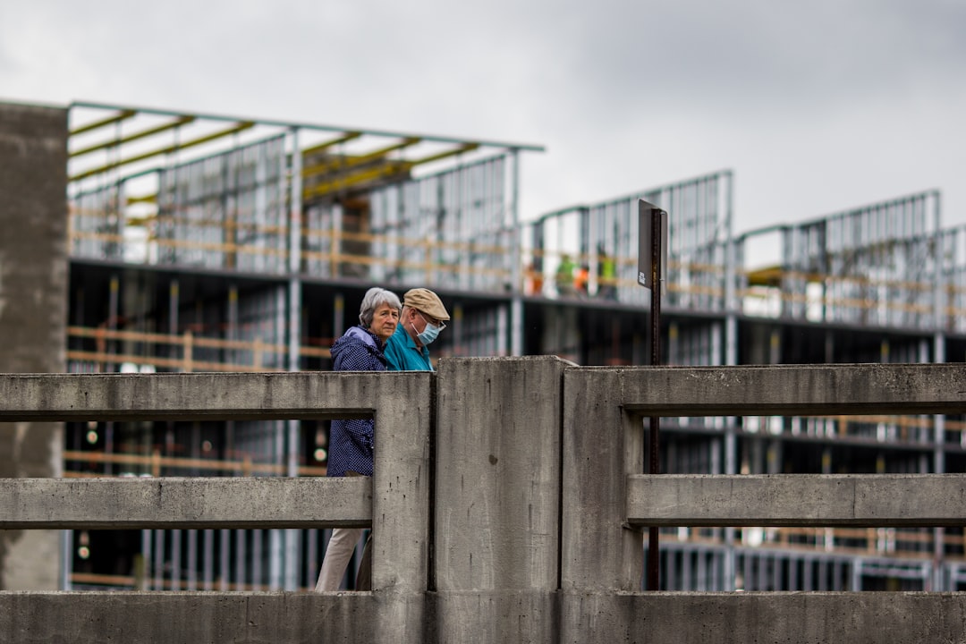 woman in blue jacket sitting on wooden bridge during daytime