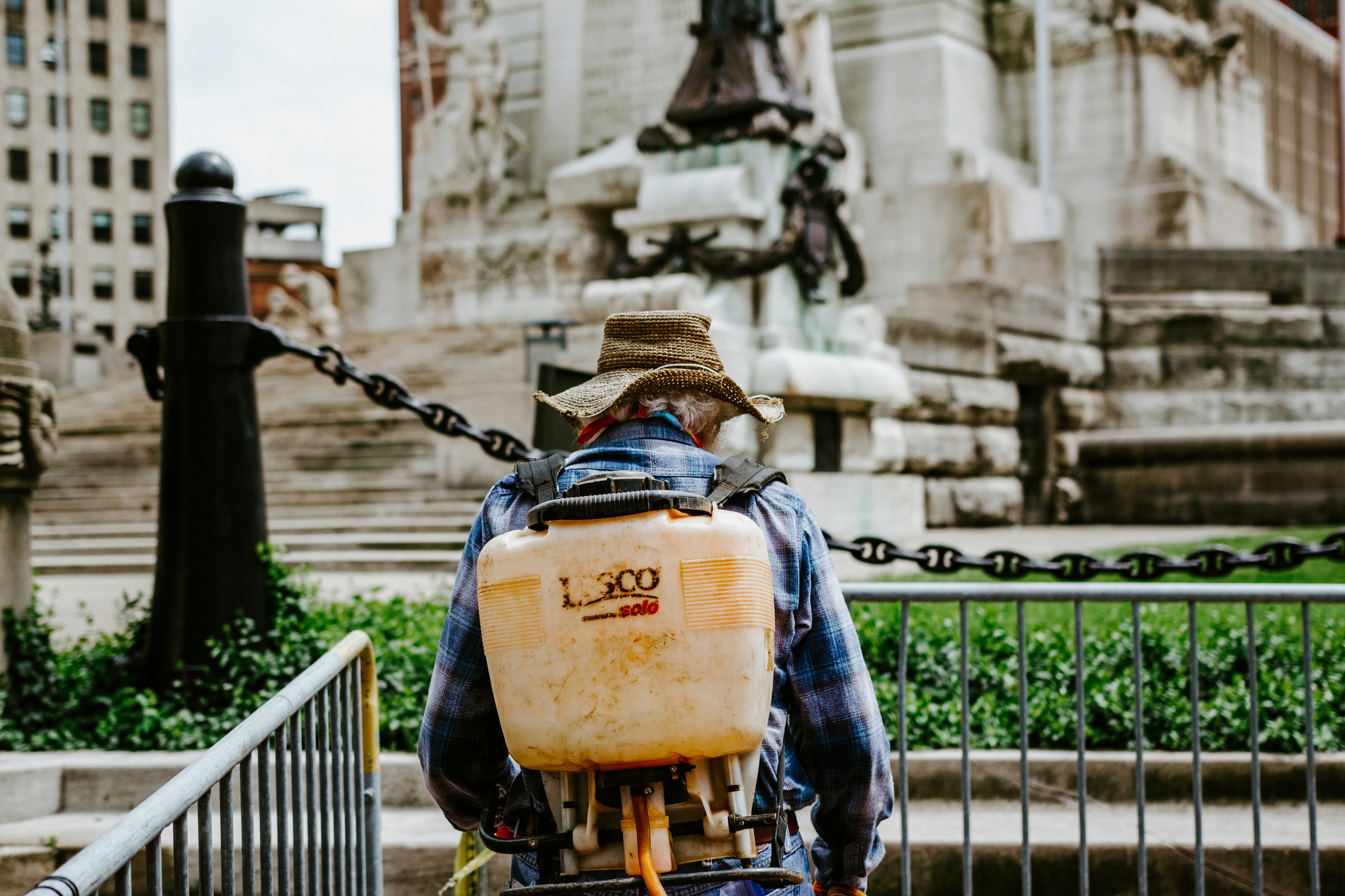 Pest control technician with spray equipment at a residential property.