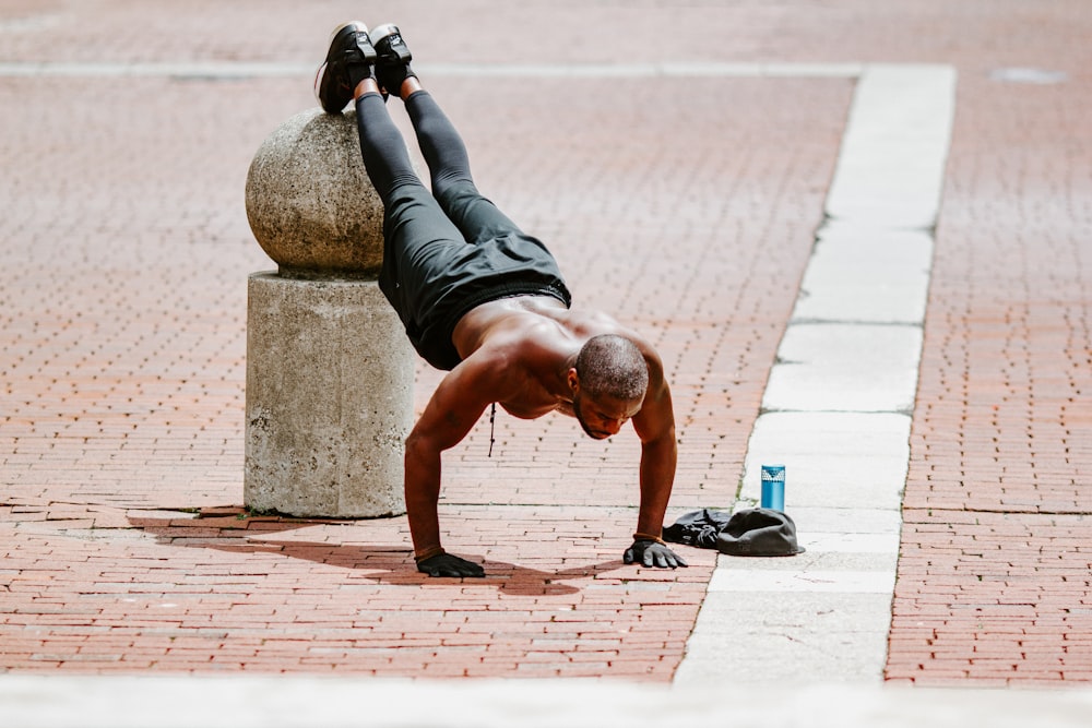 man in black tank top and black shorts lying on brown concrete floor during daytime