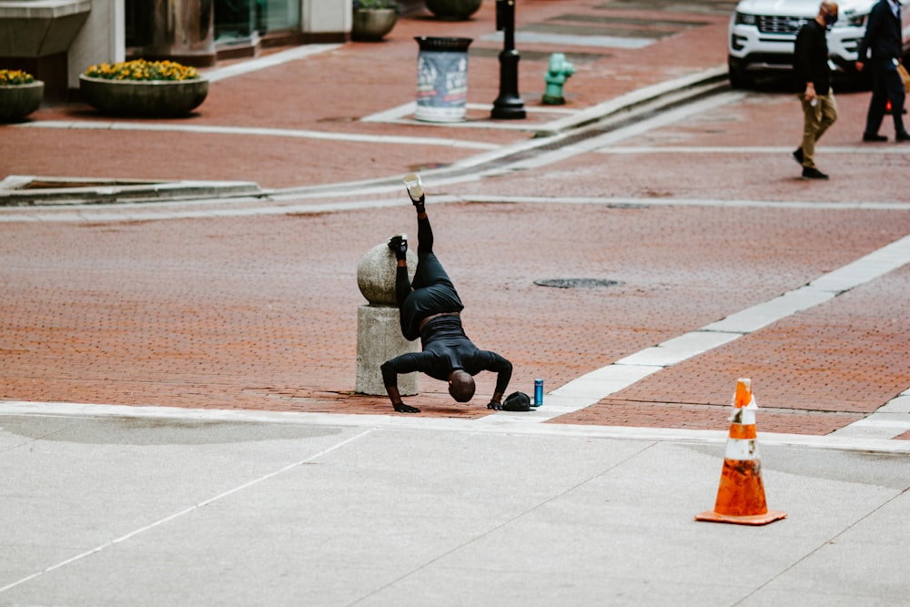 woman in black pants and gray jacket doing yoga on gray concrete floor during daytime