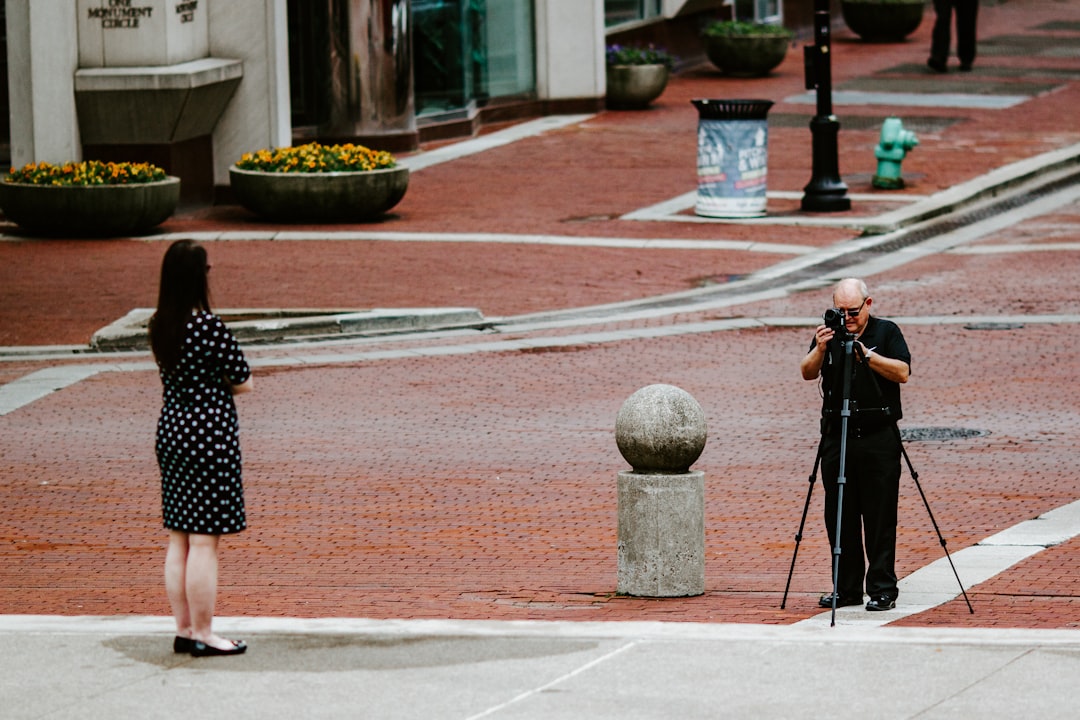 woman in black and white polka dot dress standing on sidewalk during daytime