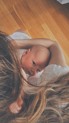 Close-up of a smiling baby looking up while being held by a caring mother.