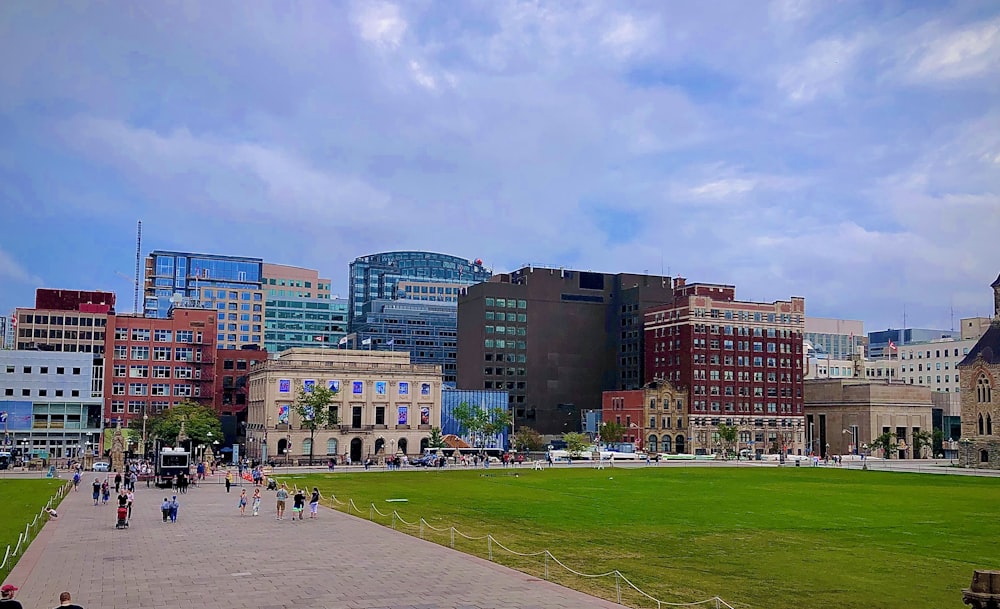 people walking on green grass field near high rise buildings during daytime