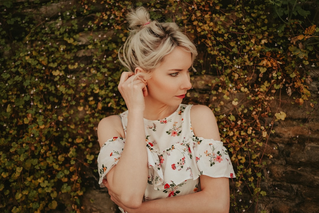 girl in white red and green floral sleeveless dress lying on brown leaves