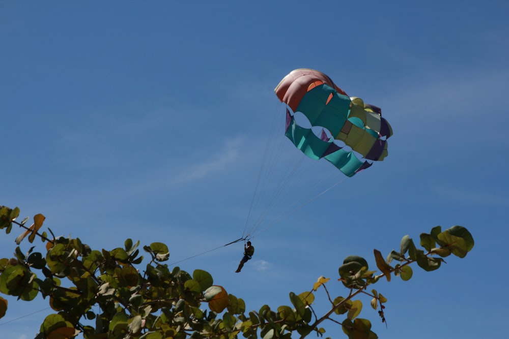 person with multi colored parachute in mid air during daytime