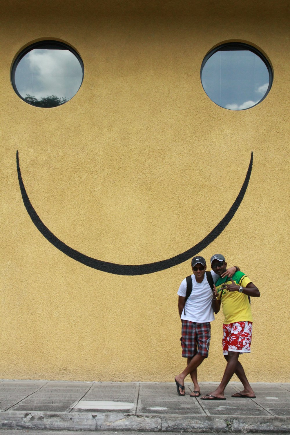 2 women standing beside yellow wall