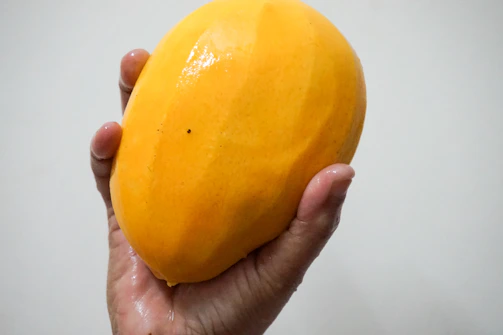 person holding yellow fruit in white room