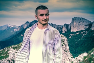 man in white and black striped long sleeve shirt standing on rocky mountain during daytime