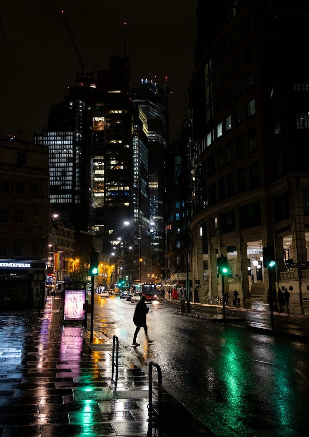man in black jacket and blue denim jeans walking on sidewalk during night time