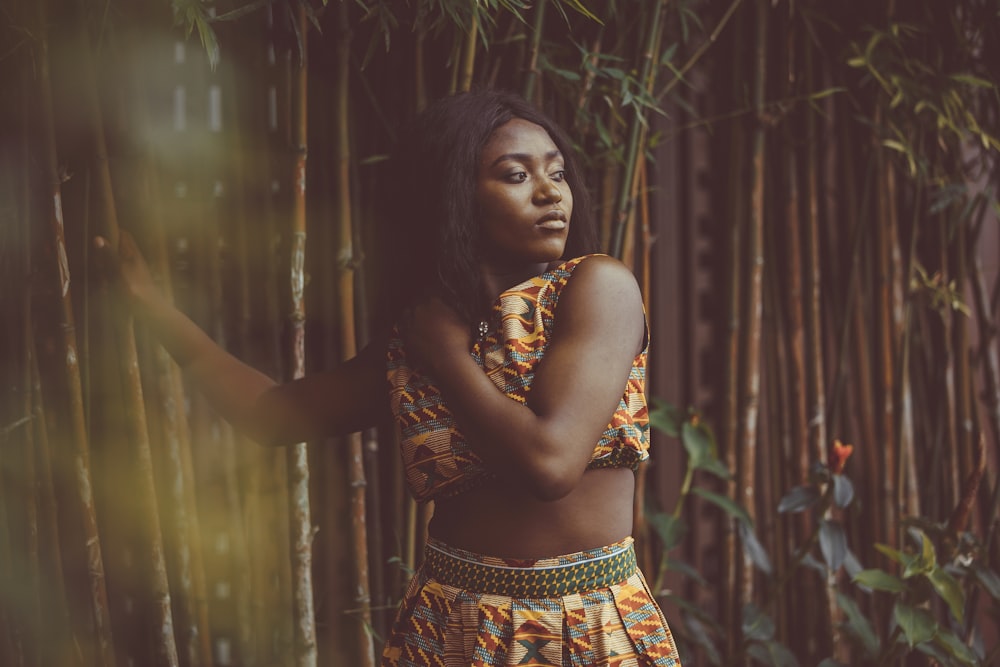 woman in brown and white floral dress standing near green plants