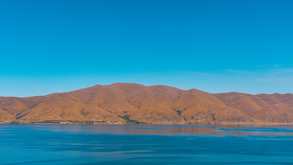 brown mountain beside blue sea under blue sky during daytime