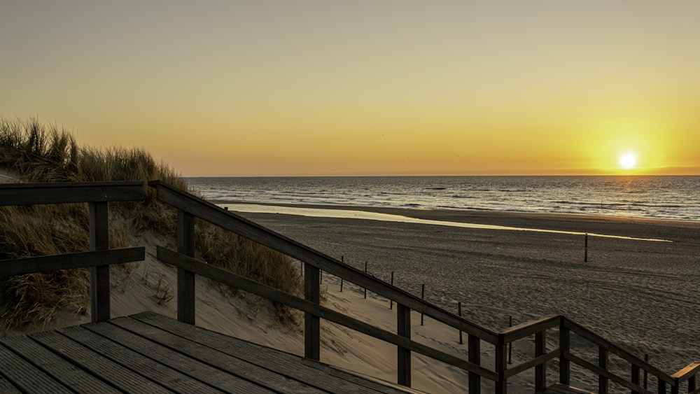 recinzione di legno marrone vicino al mare durante il tramonto