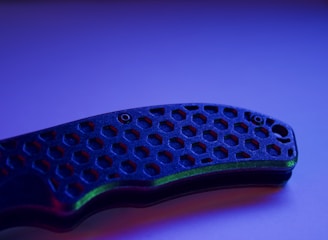 Close-up of patterned Damascus steel blade reflecting light in a workshop