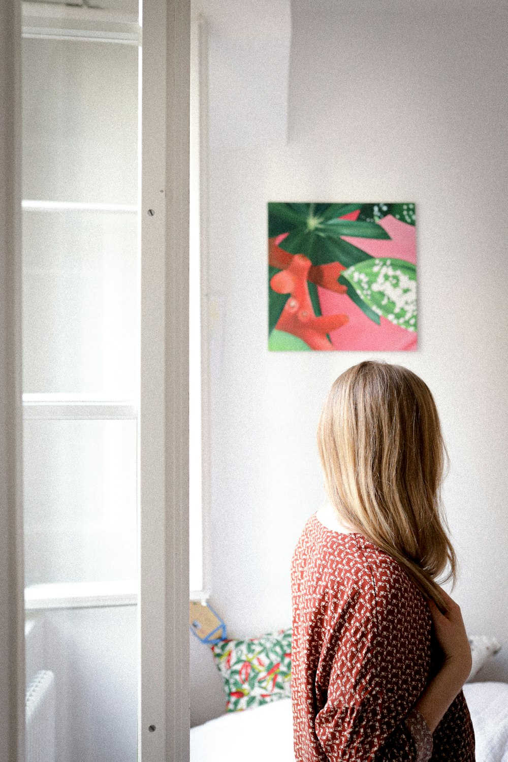 woman in red and white shirt standing near white wall