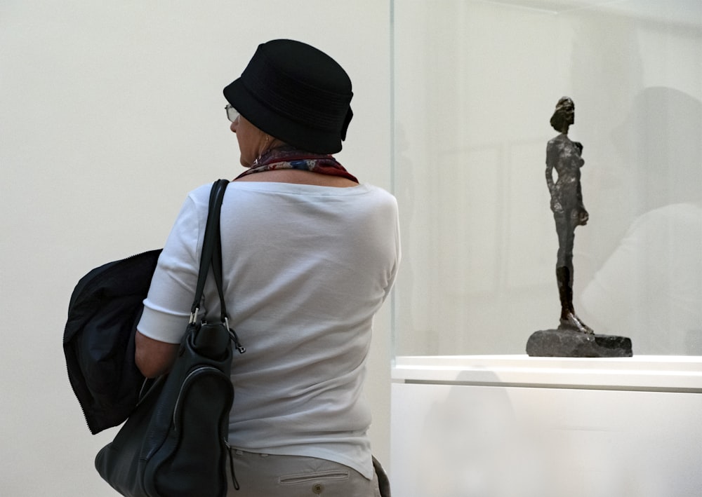 man in white long sleeve shirt and black knit cap standing in front of statue