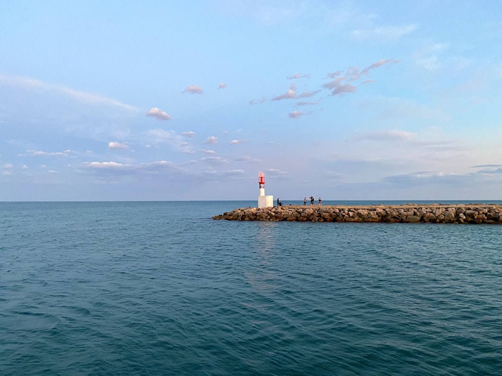 white and red lighthouse on the sea during daytime