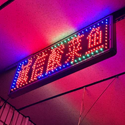 A striking illuminated sign with vibrant neon colors spelling out a brand name in a dimly lit room.