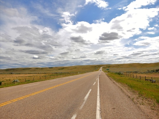 gray concrete road under white clouds and blue sky during daytime in Elkwater Canada