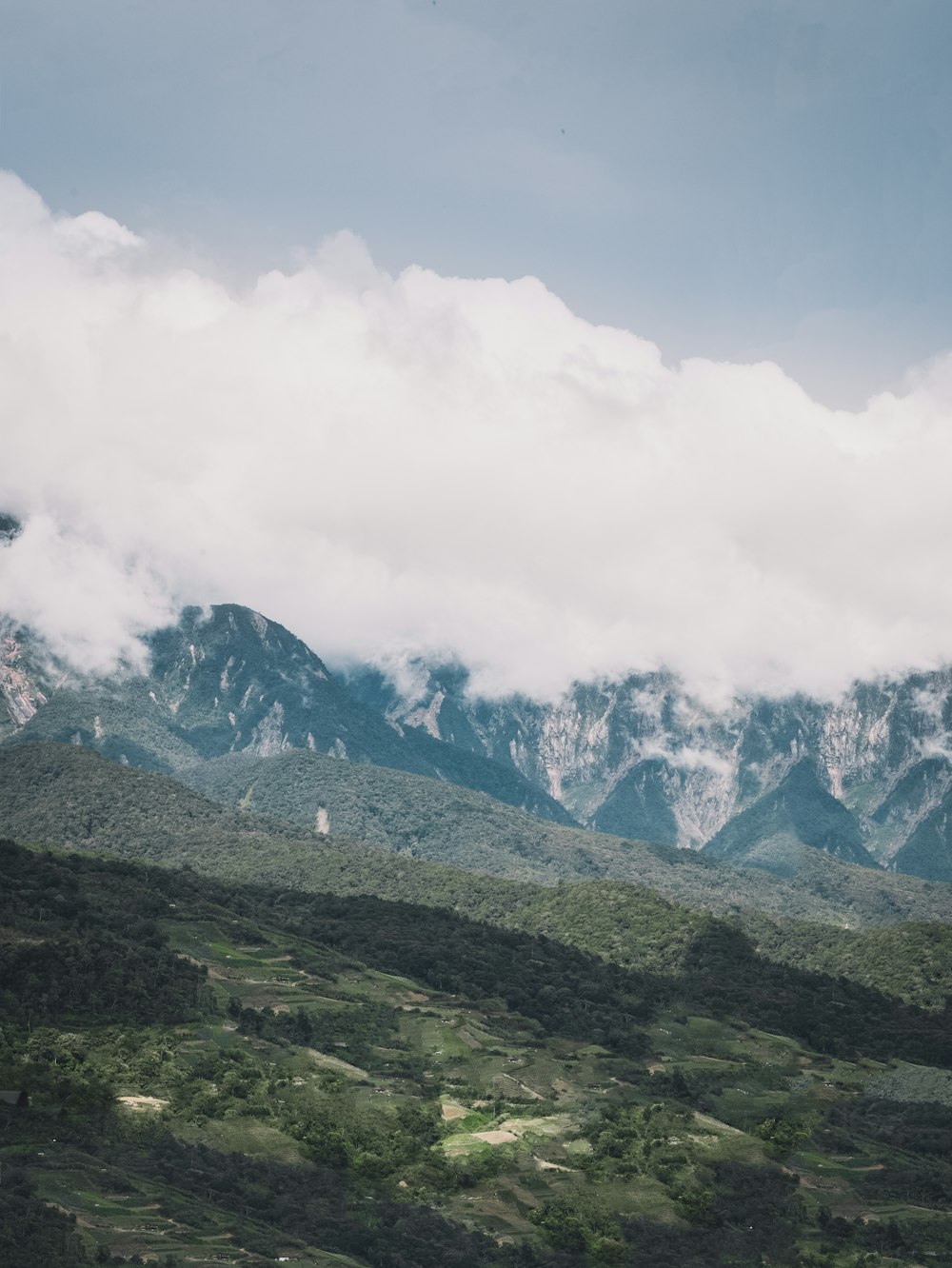 green grass field near mountain under white clouds during daytime