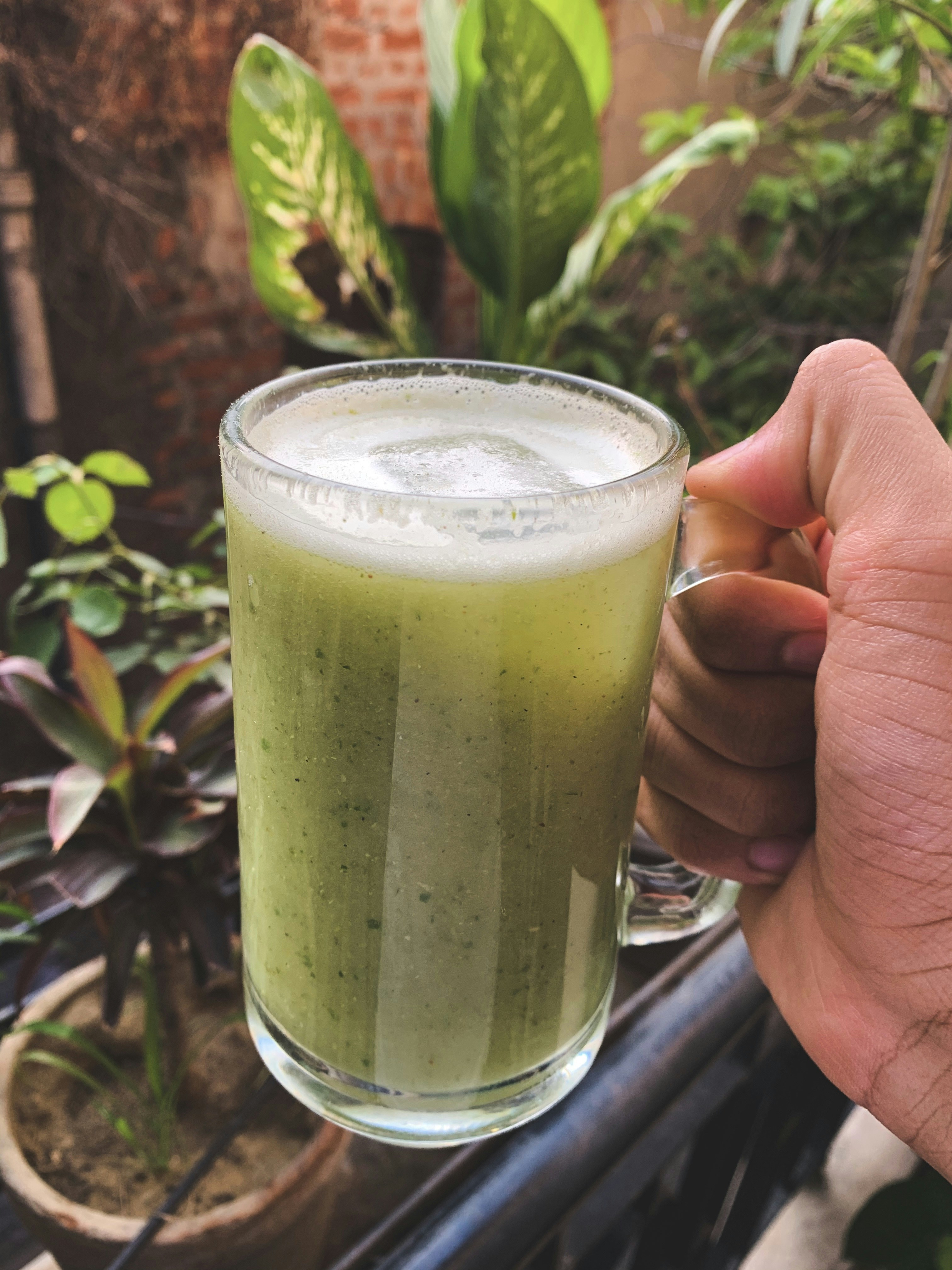 Persona sosteniendo un vaso transparente con líquido verde