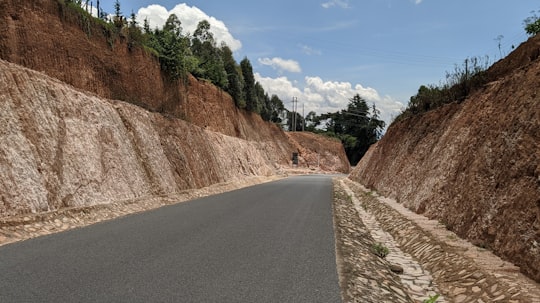 gray asphalt road between brown mountain under blue sky during daytime in Kapenguria Kenya