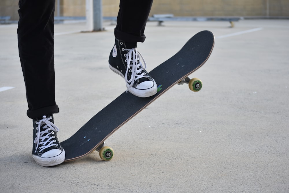 Person in schwarzen Hosen und schwarz-weißen Nike-Turnschuhen, die tagsüber Skateboard fahren