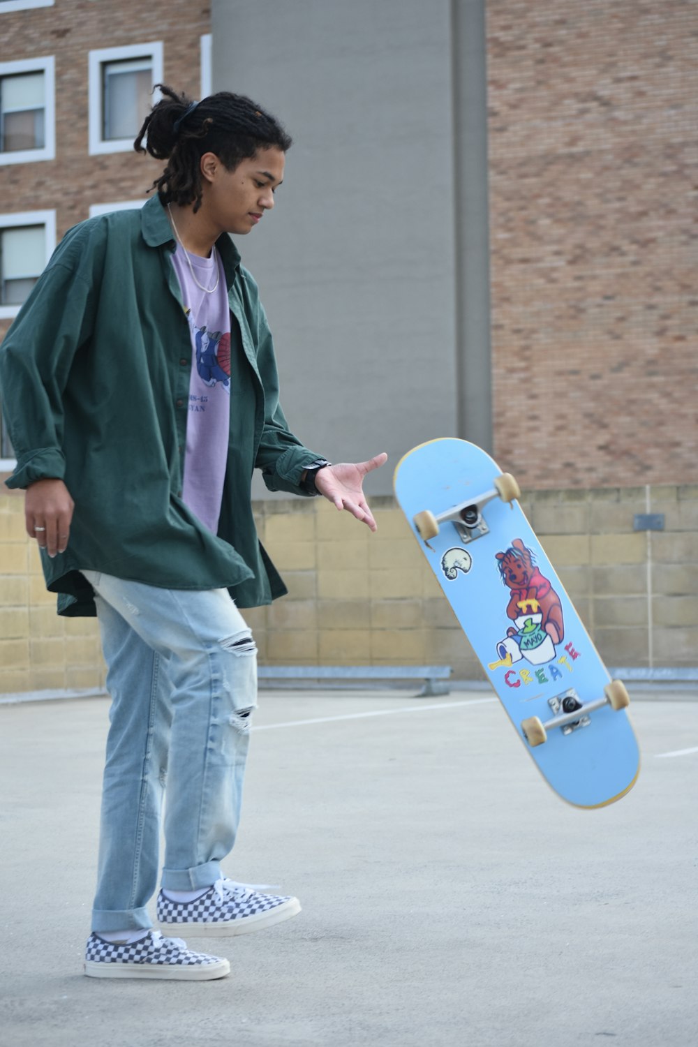 man in purple jacket holding blue skateboard