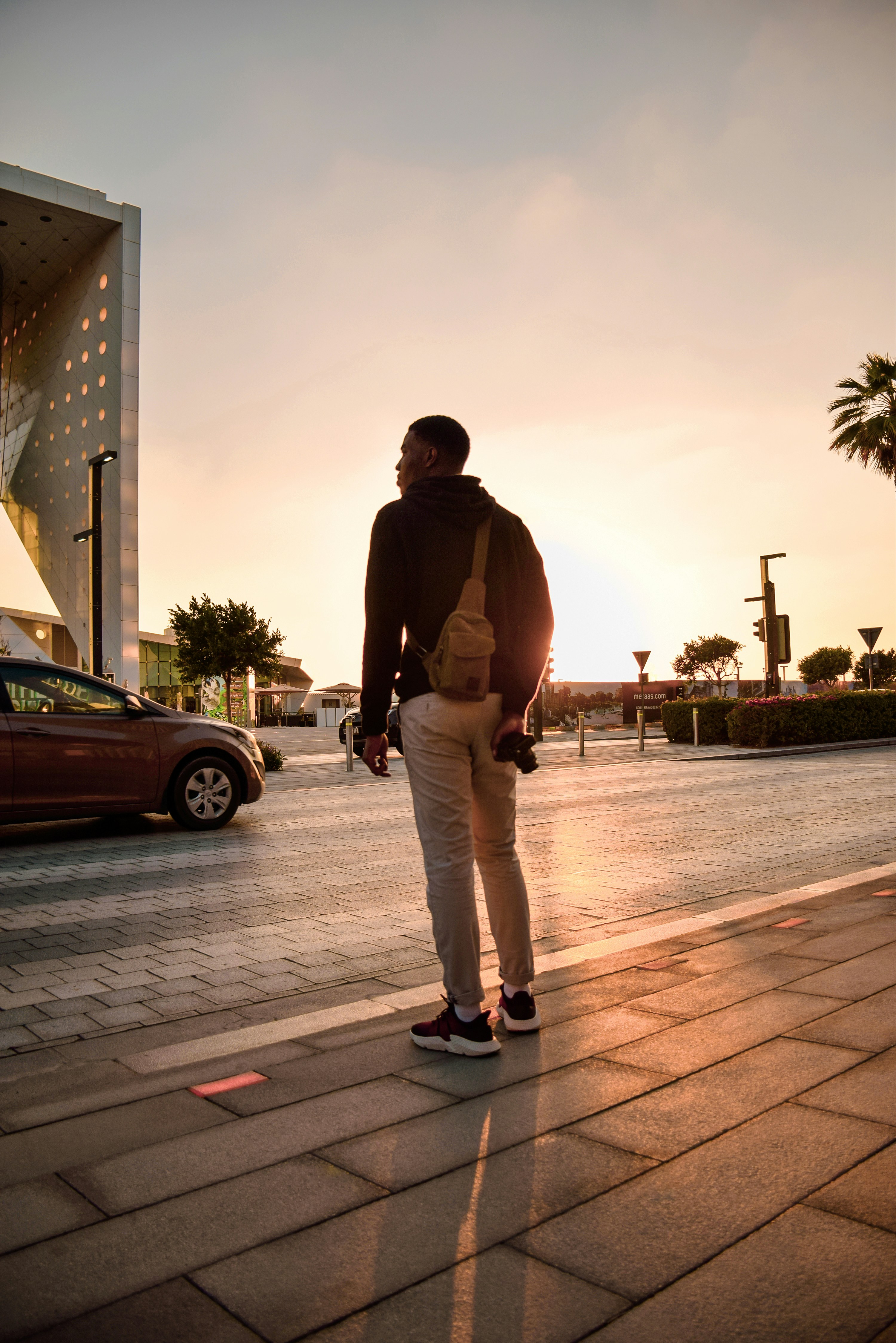 man in brown long sleeve shirt and gray pants standing on sidewalk during daytime