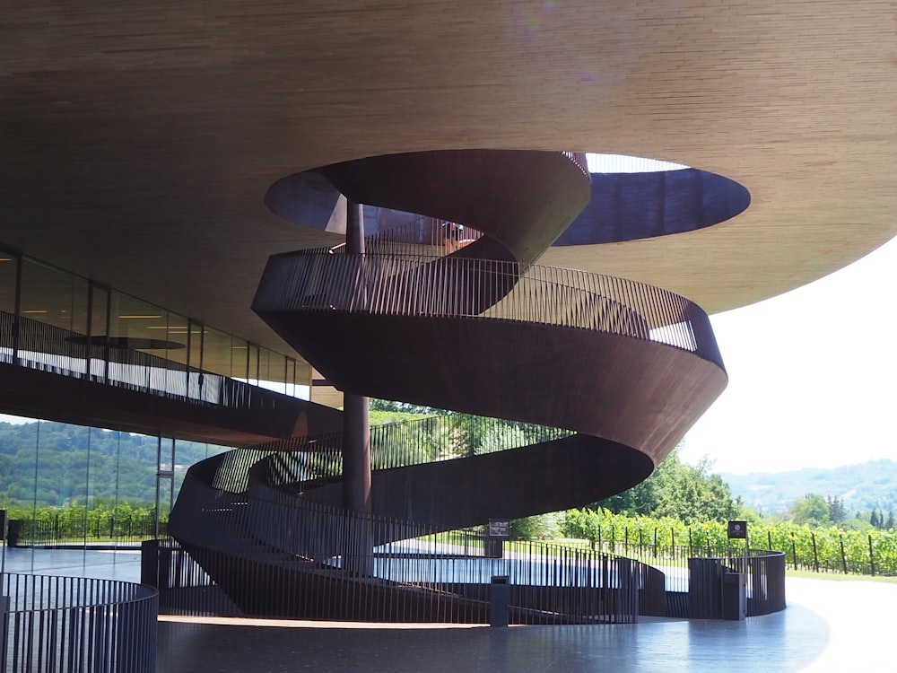 brown spiral staircase near green trees during daytime