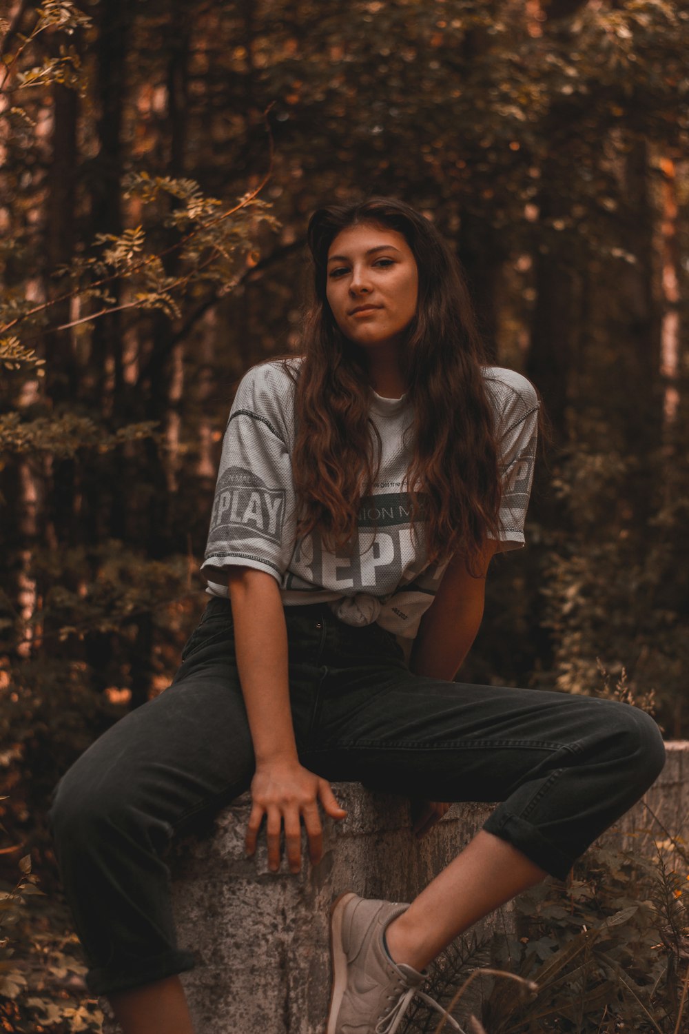 woman in white and black stripe shirt and black pants sitting on brown wooden seat