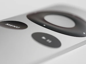 Close-up of a remote control with golden accents on a sleek black surface.