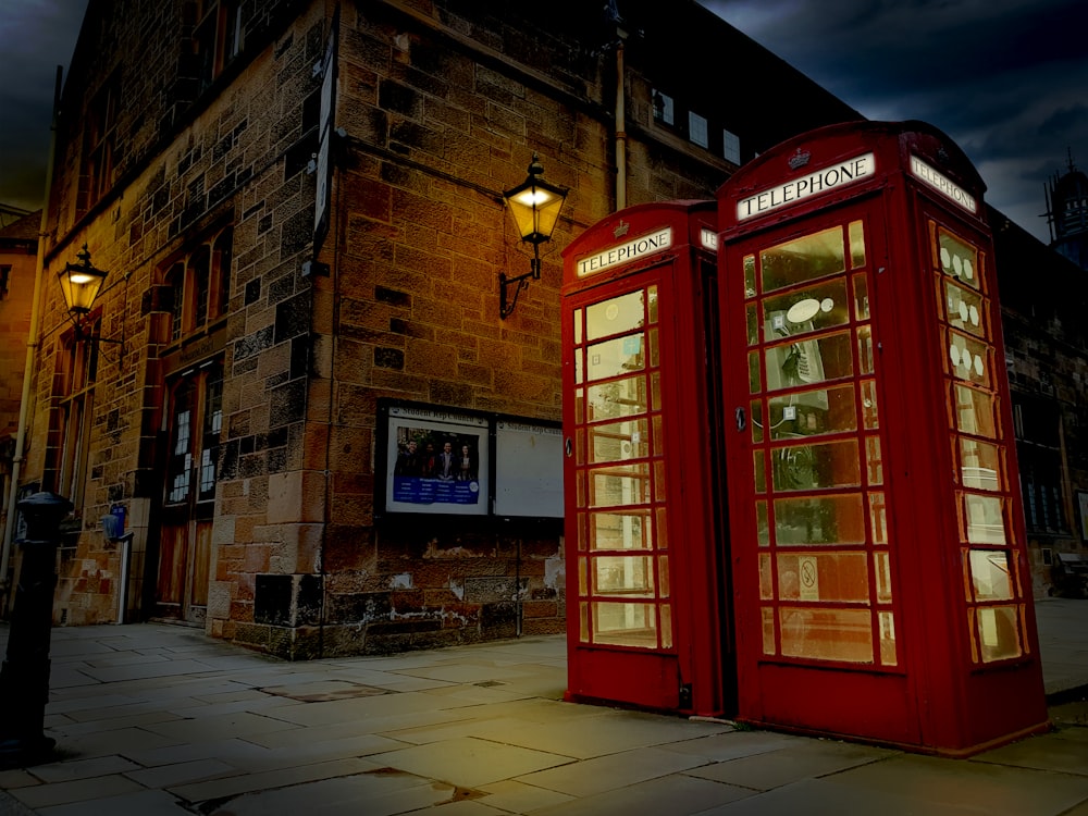 red telephone booth in front of brown brick building