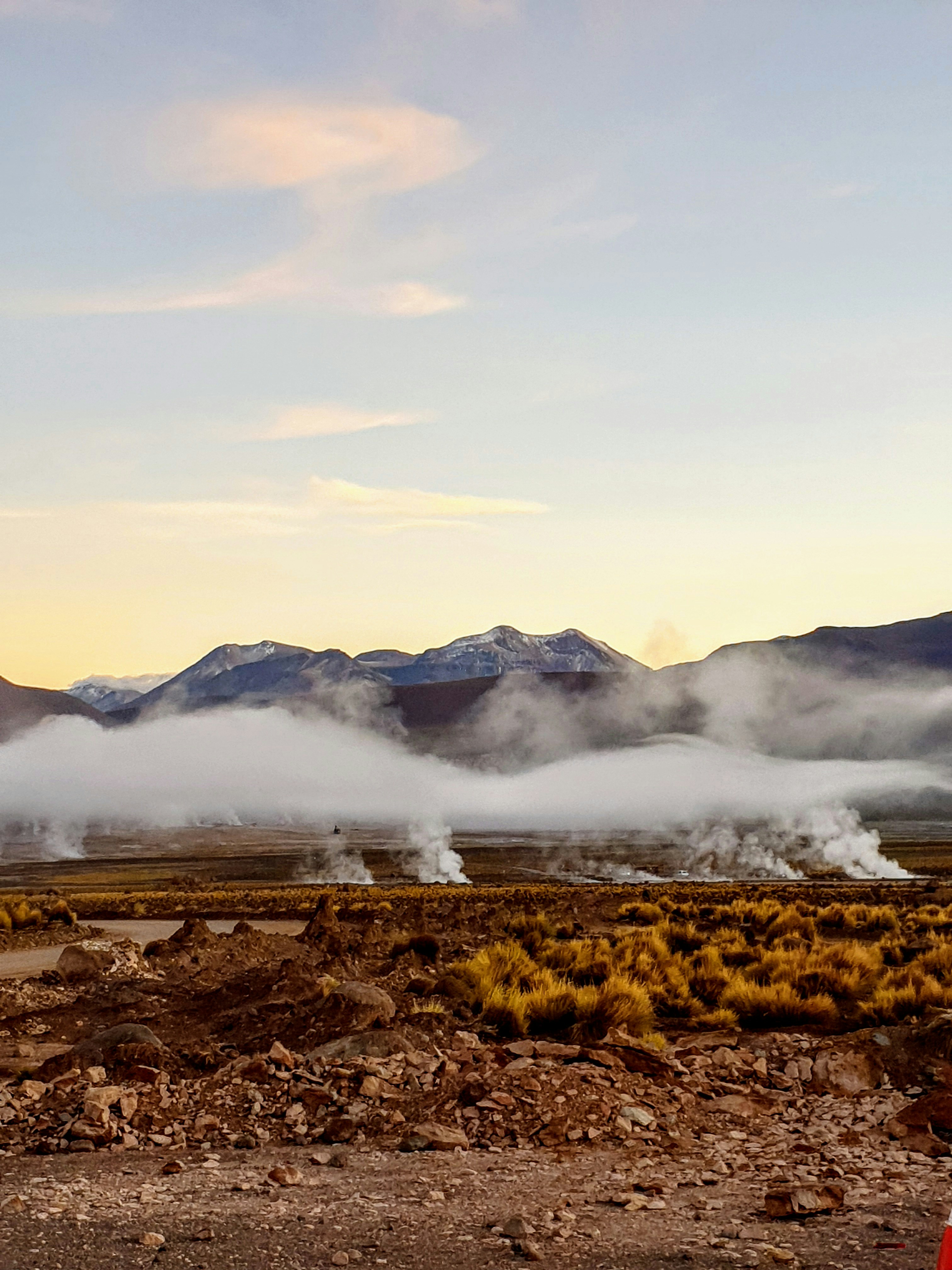 brown grass field near mountain under white clouds during daytime