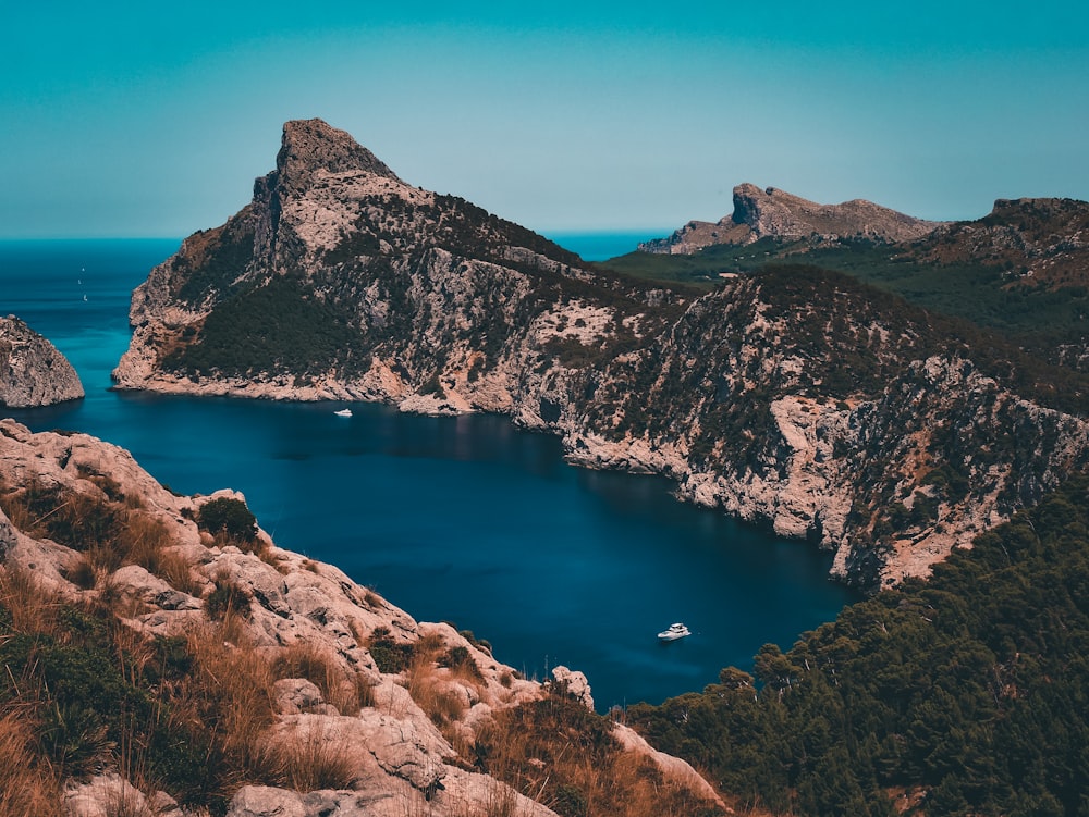 brown rocky mountain beside blue sea under blue sky during daytime