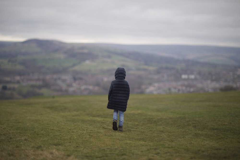 person in black jacket standing on green grass field during daytime