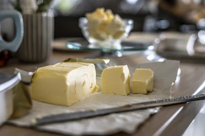 Golden butter blocks resting on rustic parchment paper with a butter knife beside them