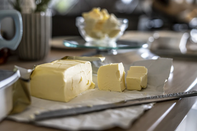 A block of golden butter partially sliced on a kitchen counter
