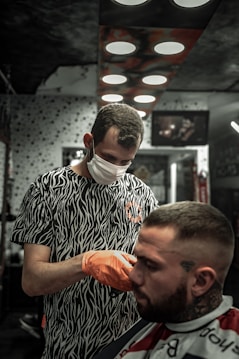 man in black and white crew neck shirt holding orange fruit